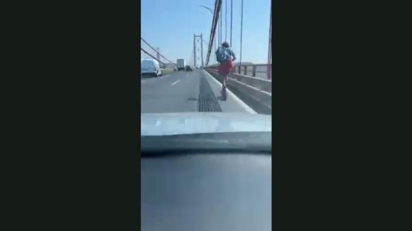 Homem atravessa a ponte, em Lisboa, de trotineta